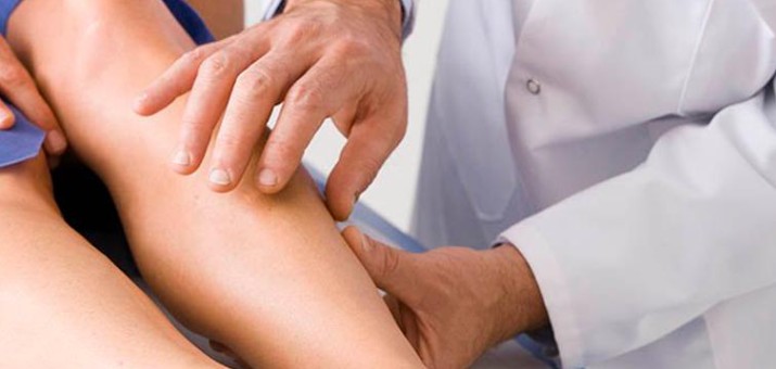 Mujer examinando sus piernas por historia familiar de varices